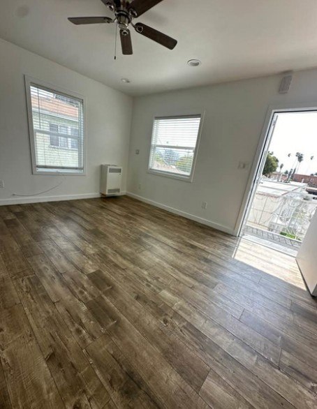 A room with a ceiling fan and wood flooring.